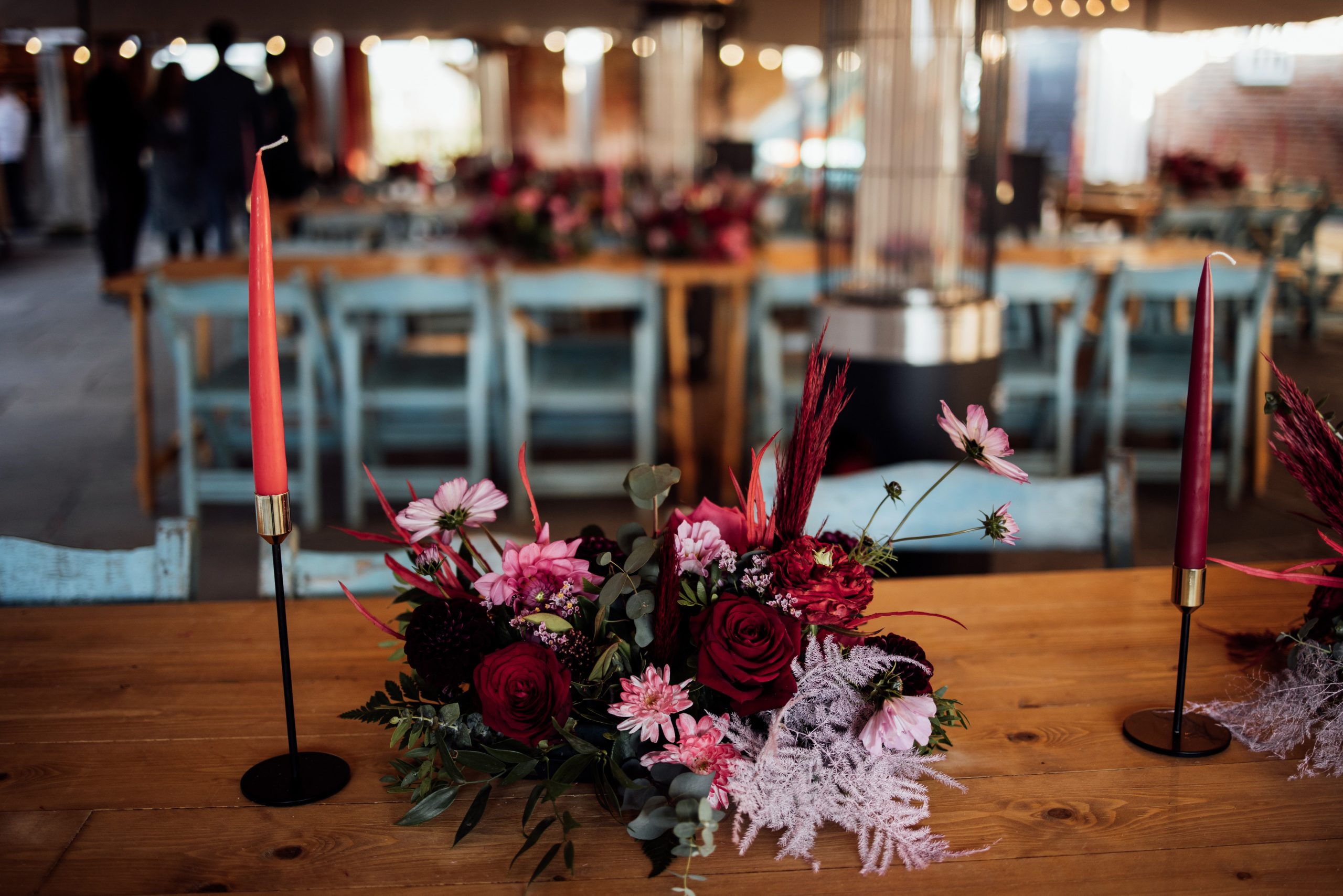 flowers and coloured candles on wooden trestle tables with blue chairs