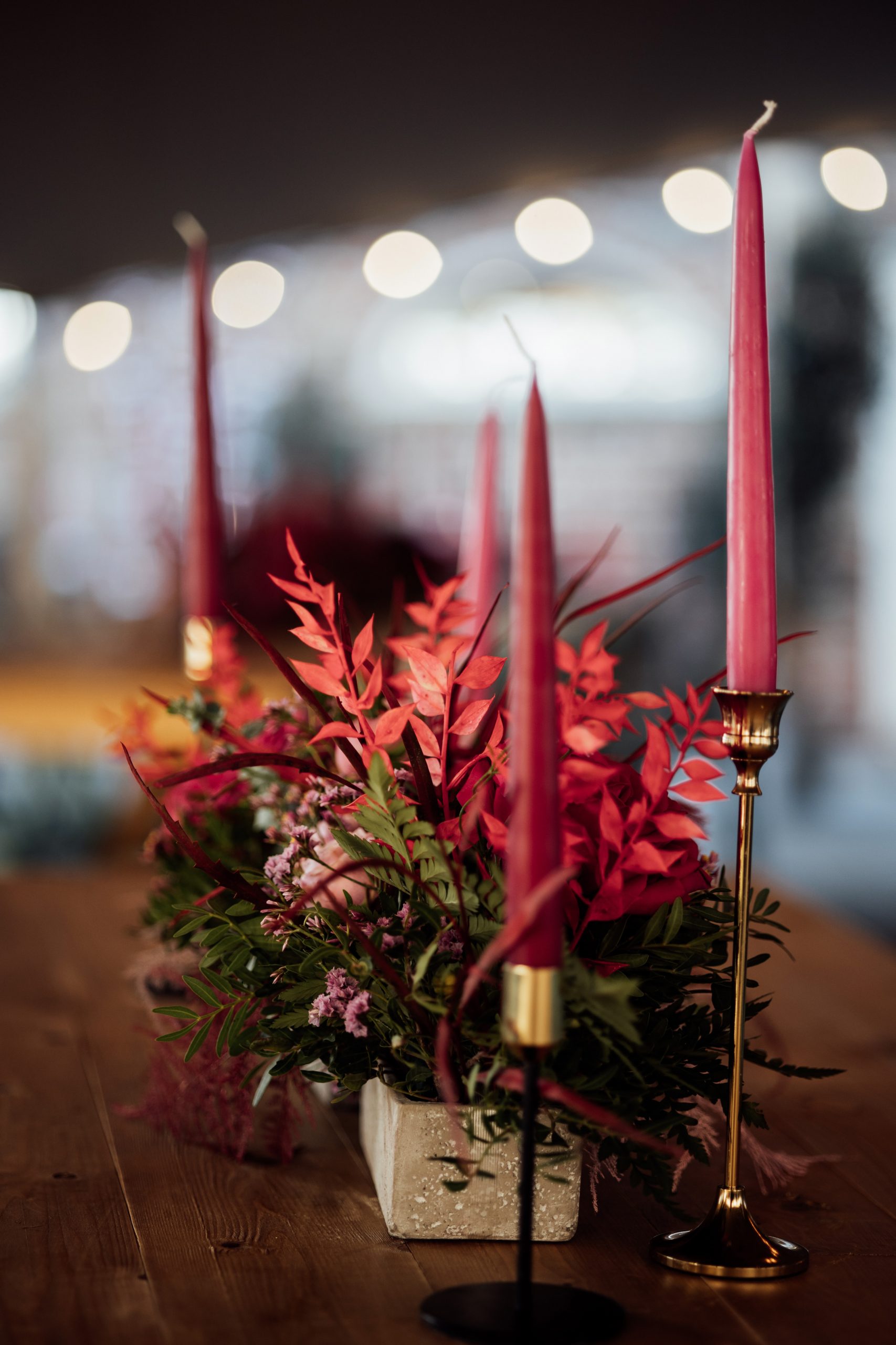 A display of pink and red florals and candles on a trestle table