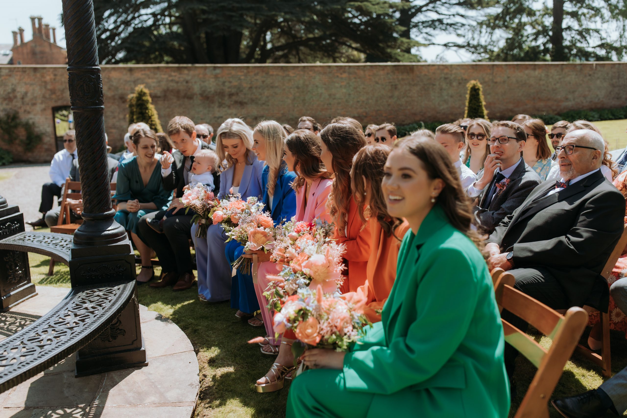 Guest sitting ready for ceremony at Garthmyl Hall. Bridesmaids in colourful rainbow suits