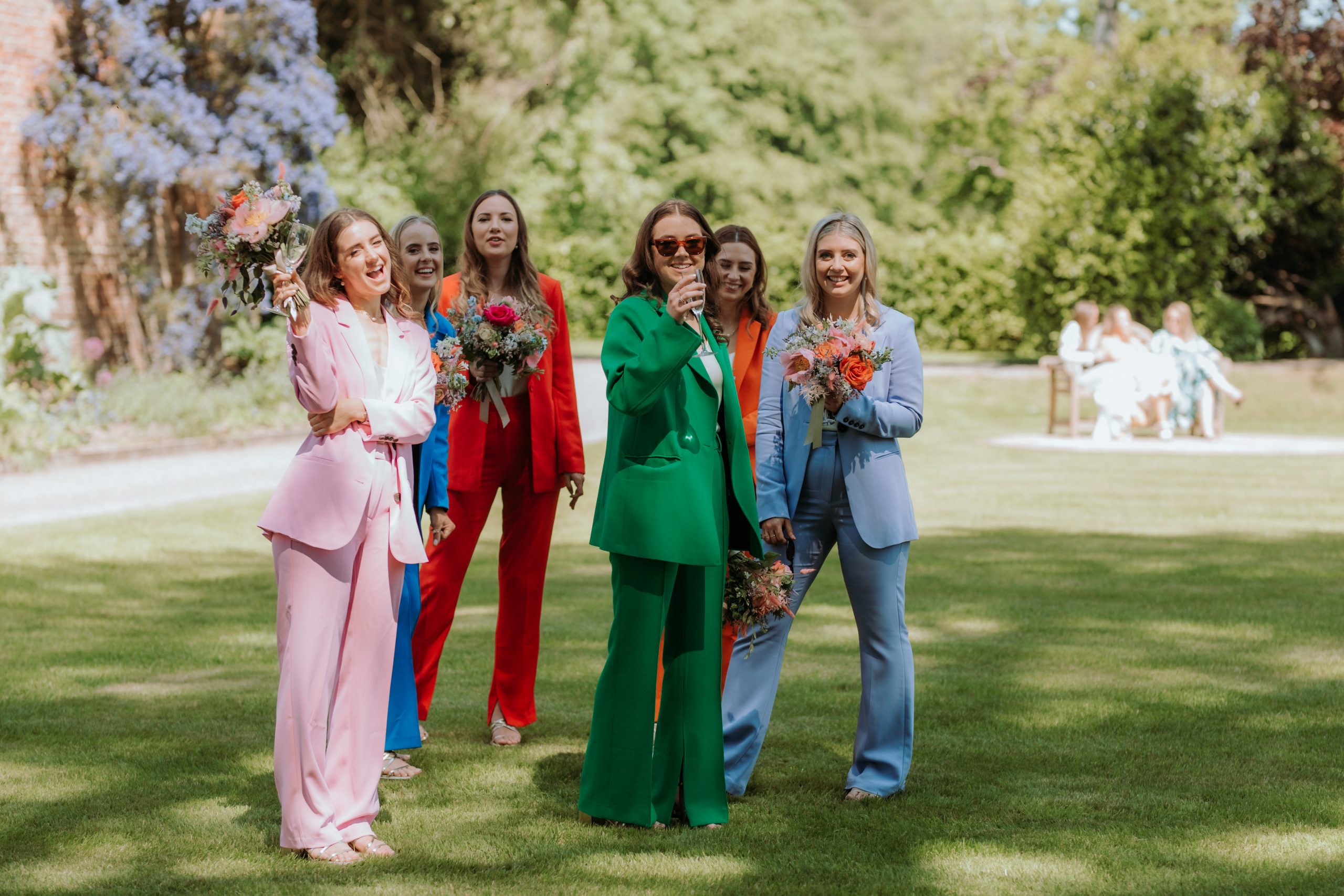 Bridesmaids in rainbow coloured suits playing garden games