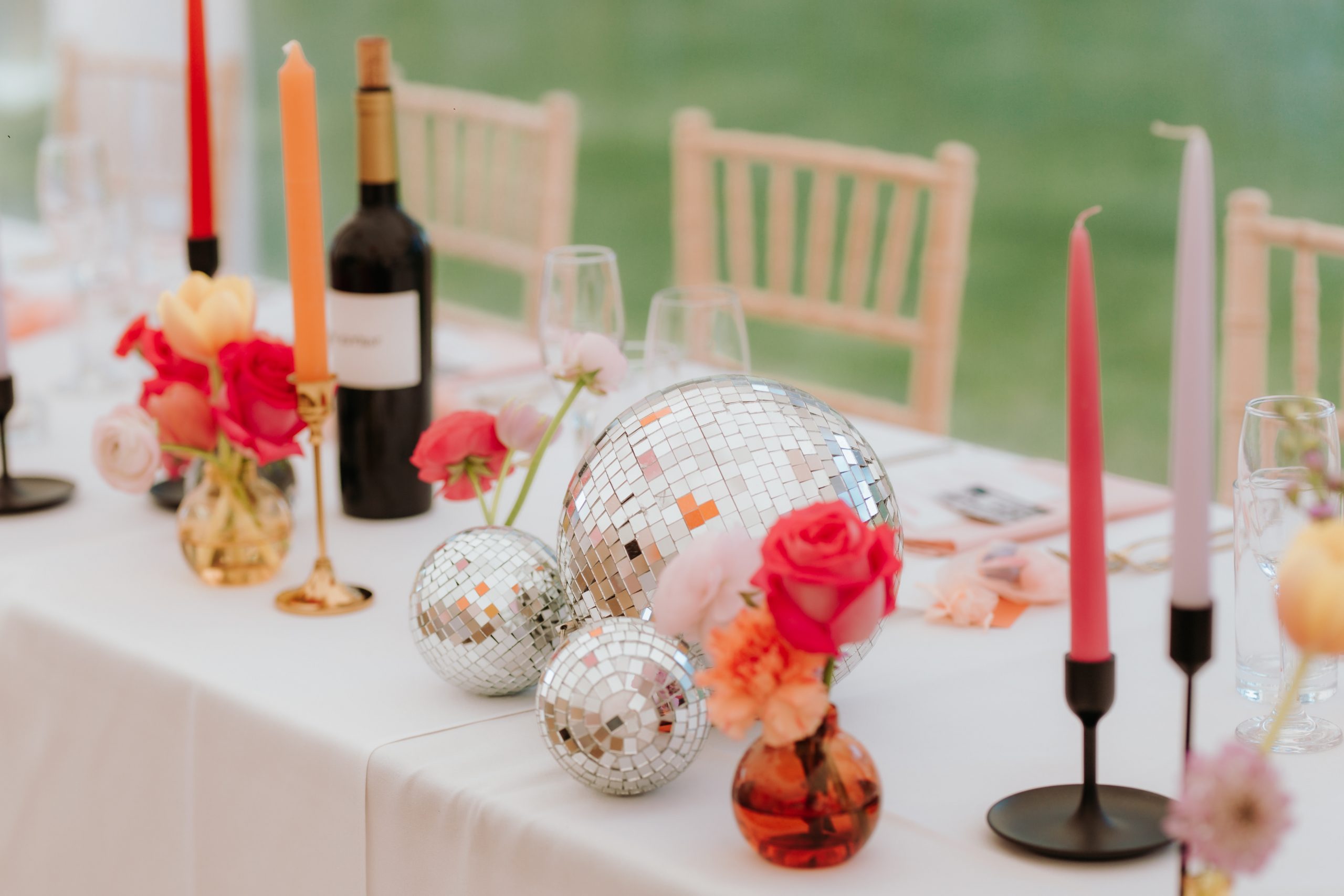 A colour table set up with disco balls styled next to candles and flowers
