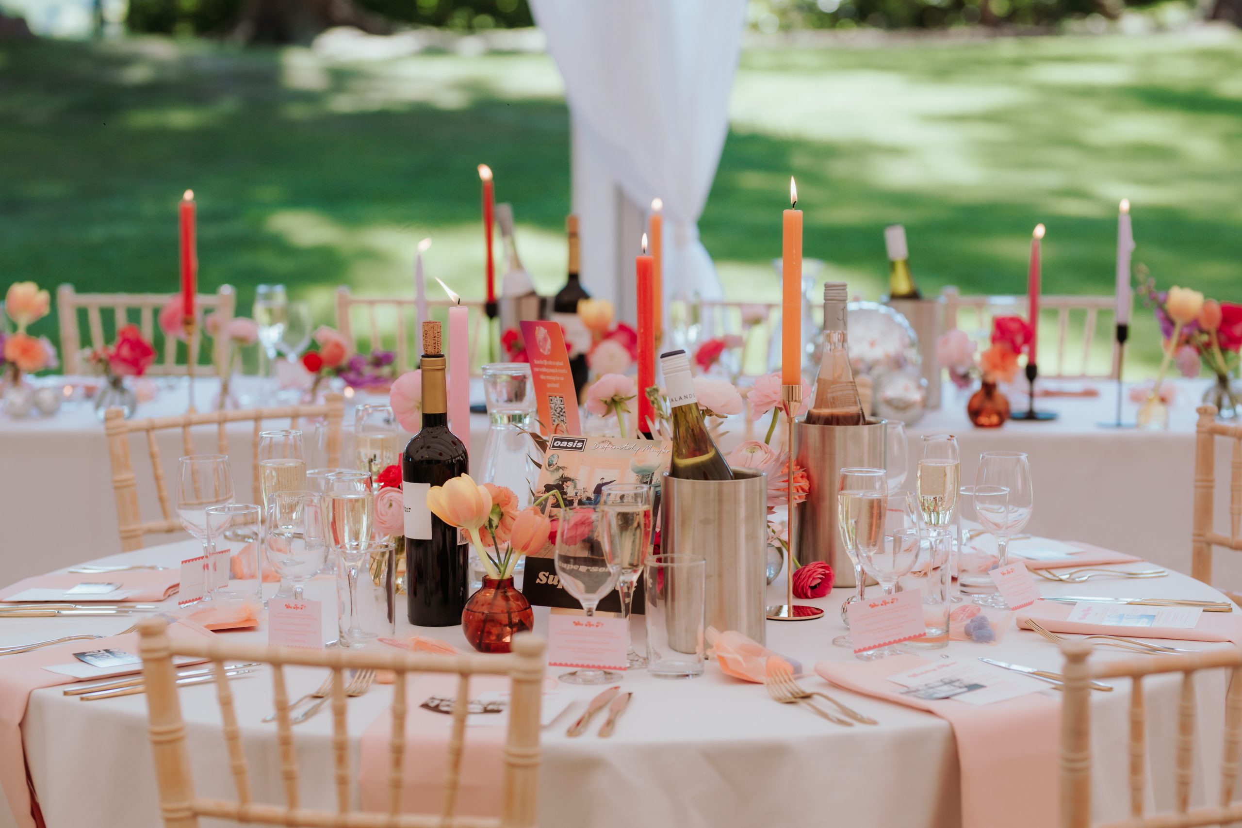 A colourful table setting filled with pink, orange and red candles and flowers