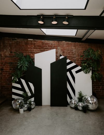 Black and white wedding ceremony backdrops with disco balls styled with plants on the floor