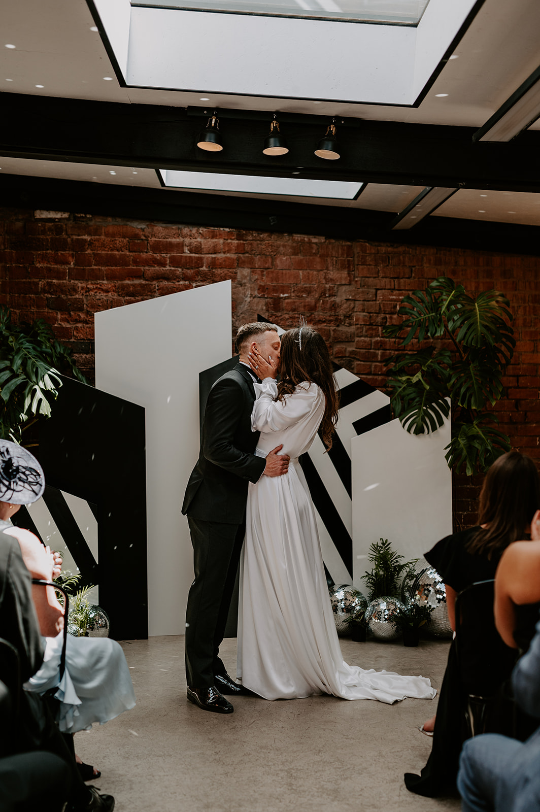 bride and groom kissing in front of black and white ceremony backdrop
