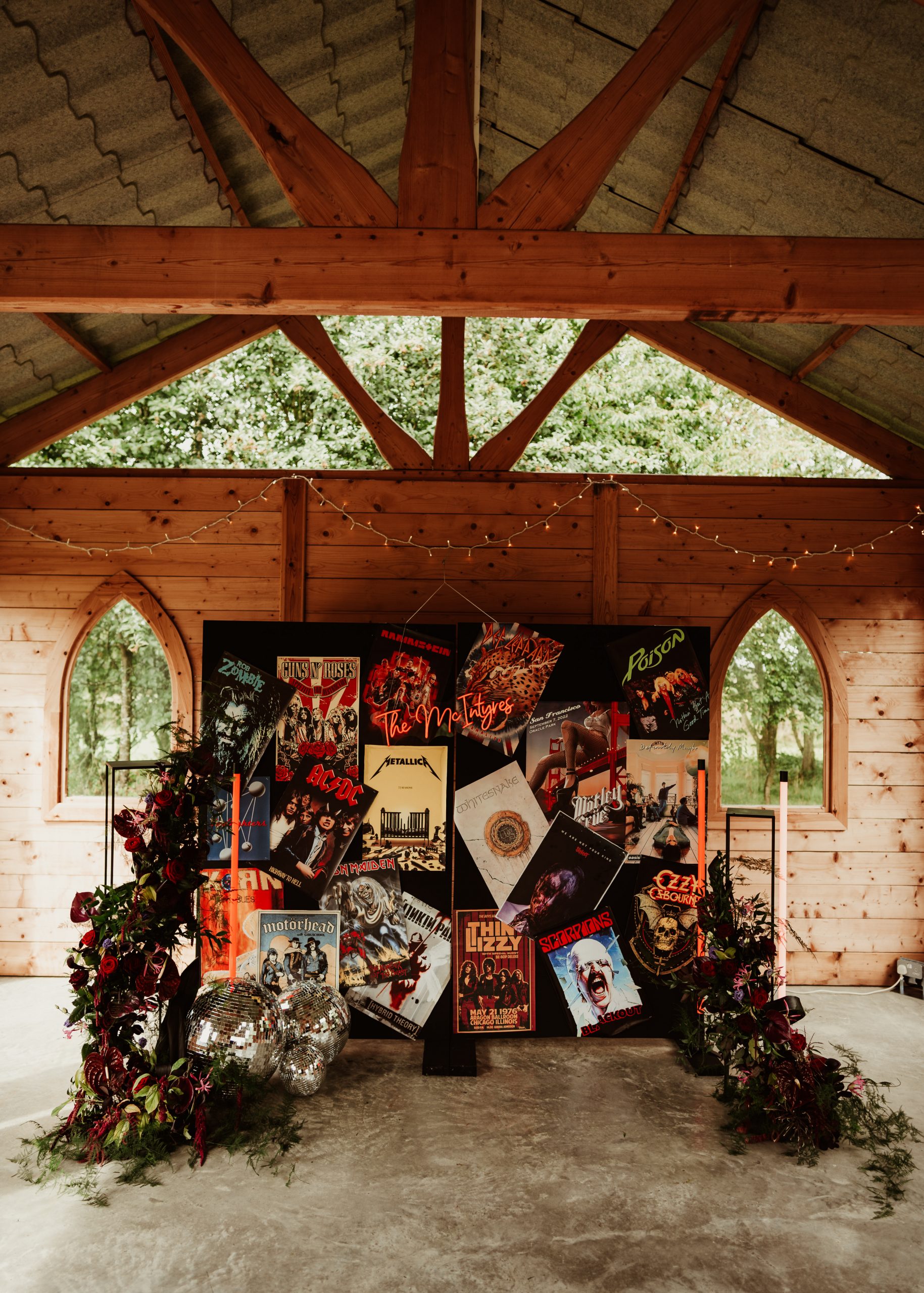 a ceremony backdrop filled with rock posters neon stands and florals