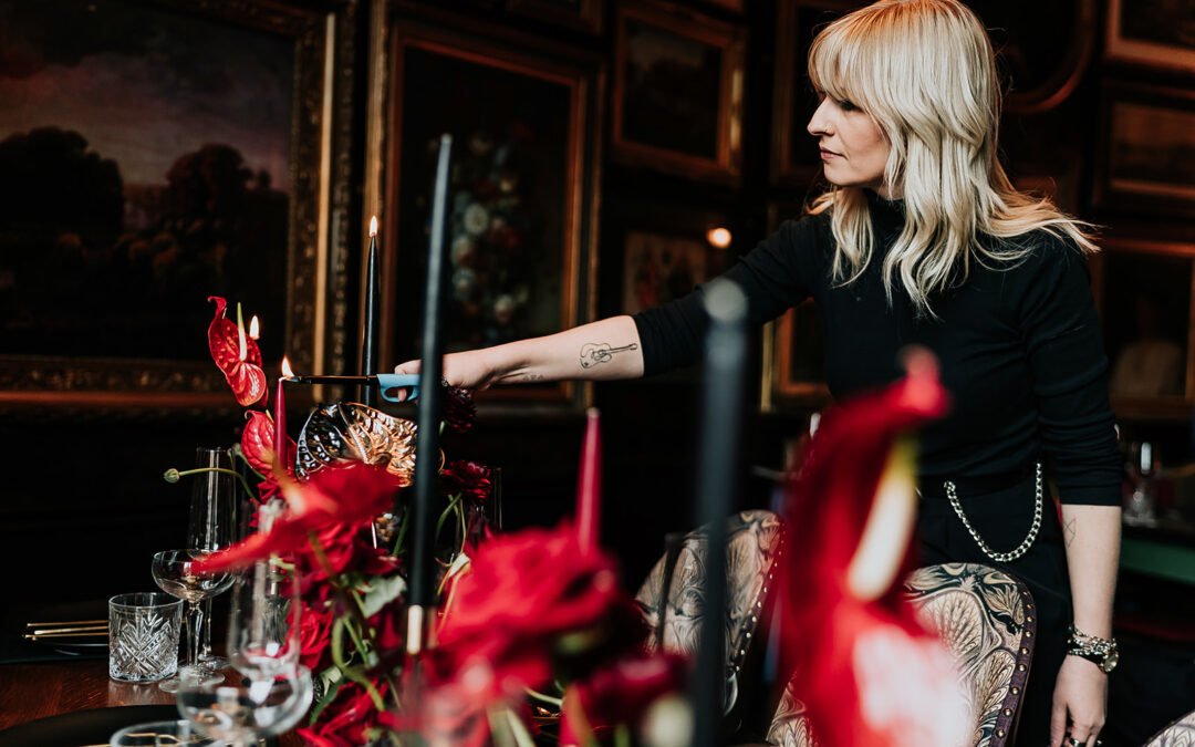 woman dressed in black lighting candles which are displayed on a goth themed wedding table